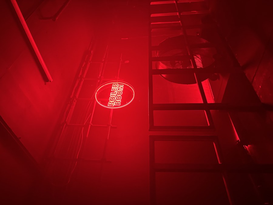 Boiler Room neon sign glowing red above a railing